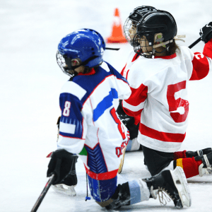 Three Squirt Ice Hockey Players taking a knee during a game