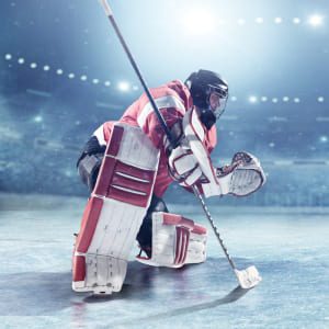 Goalie in full equipment with Hockey Glove, goalie Blocker, leg pads, goalie stick. Goalie uniform in red and white