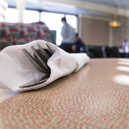 Picture of a table at a diner with fork, knife and spoon wrapped in a white napkin