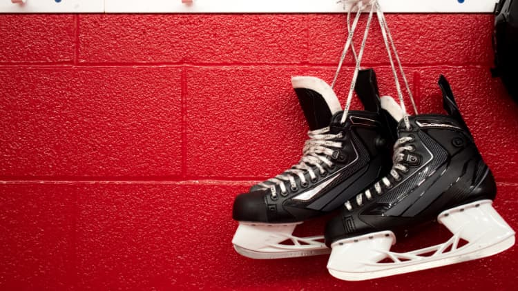 Red painted wall with men's ice hockey skates hanging for High School Hockey