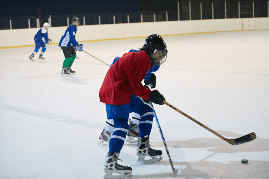 Two ice hockey players one in red and one blue next to each other during a play on ice