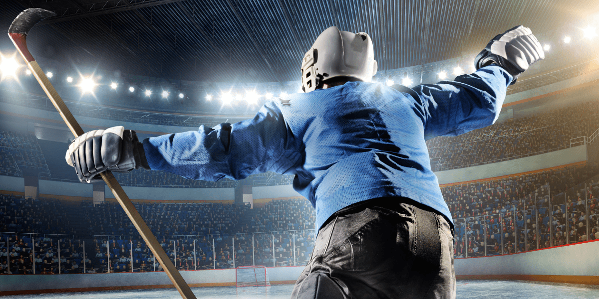 Ice Hockey child celebrating a goal with hands in the air and a hockey stick