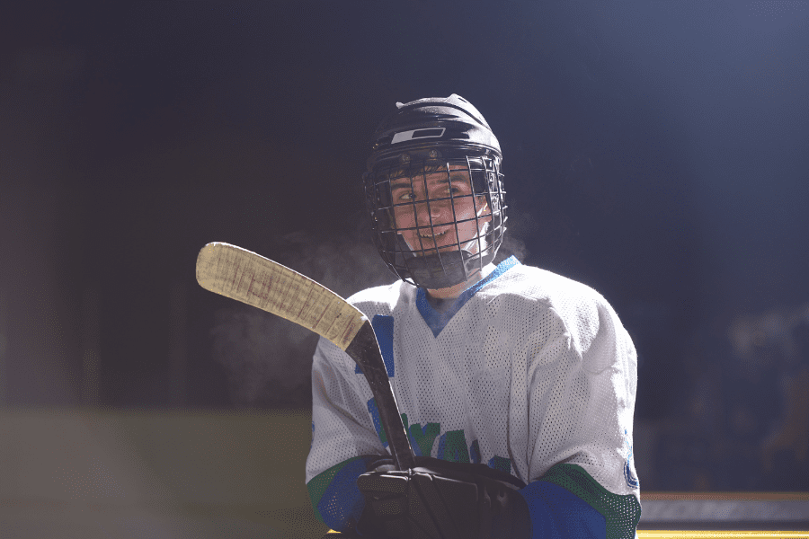 Older ice hockey player holding stick and smiling