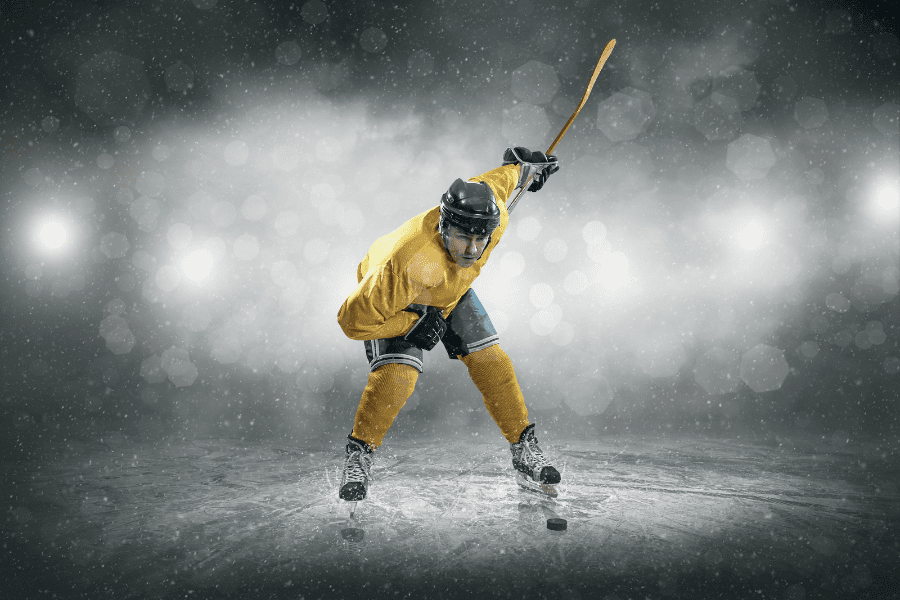 hockey player in yellow jersey taking successful slap shot