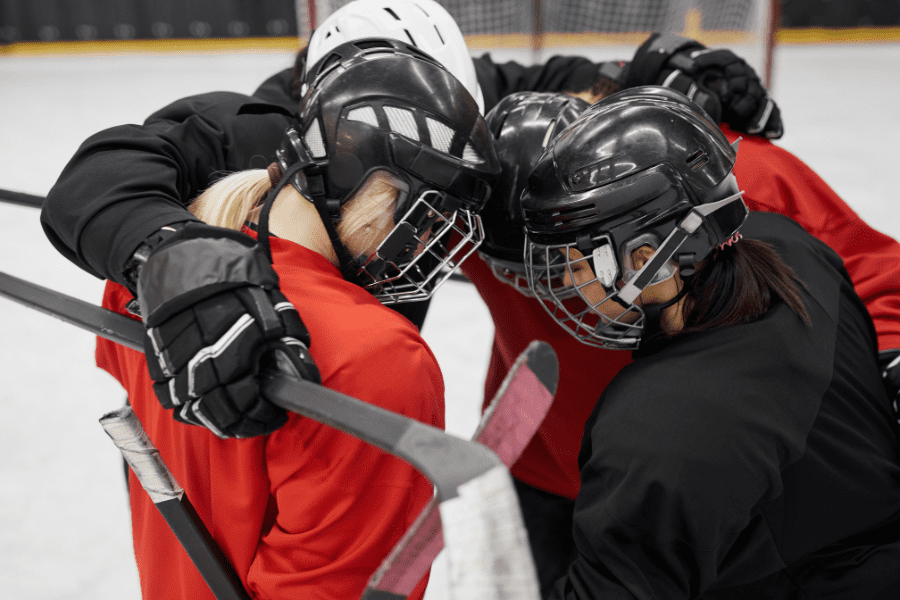 Group of 4 hockey players helmets down in a huddle