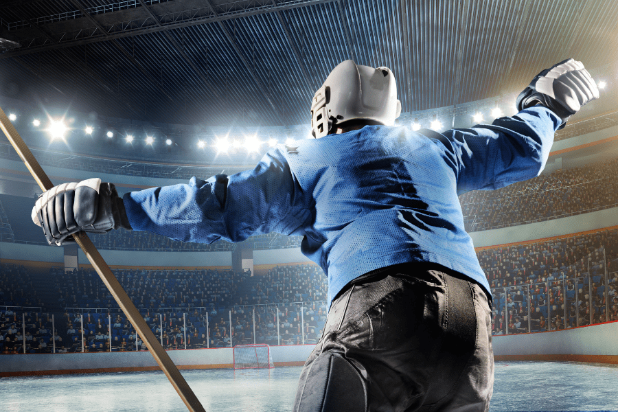 Ice Hockey player in Blue and white helmet and stick celebrating a win