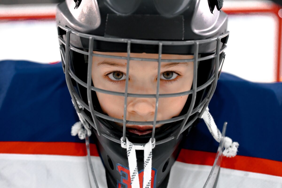 young boy in ice hockey black helmet and blue, red and white jersey